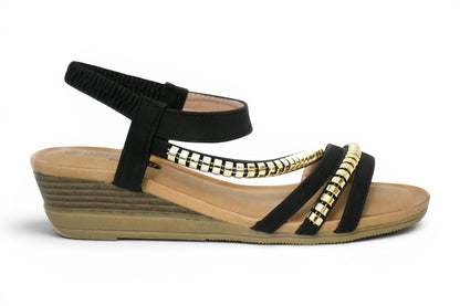 sandalia de talla grande para mujer en color negro y tachuelas en la zona del empeine con agarre al tobillo elástico y cuña baja en tono madera