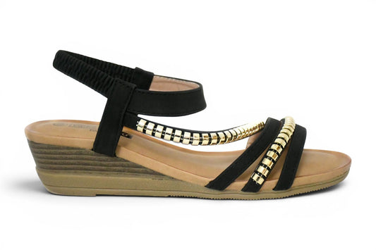 sandalia de talla grande para mujer en color negro y tachuelas en la zona del empeine con agarre al tobillo elástico y cuña baja en tono madera